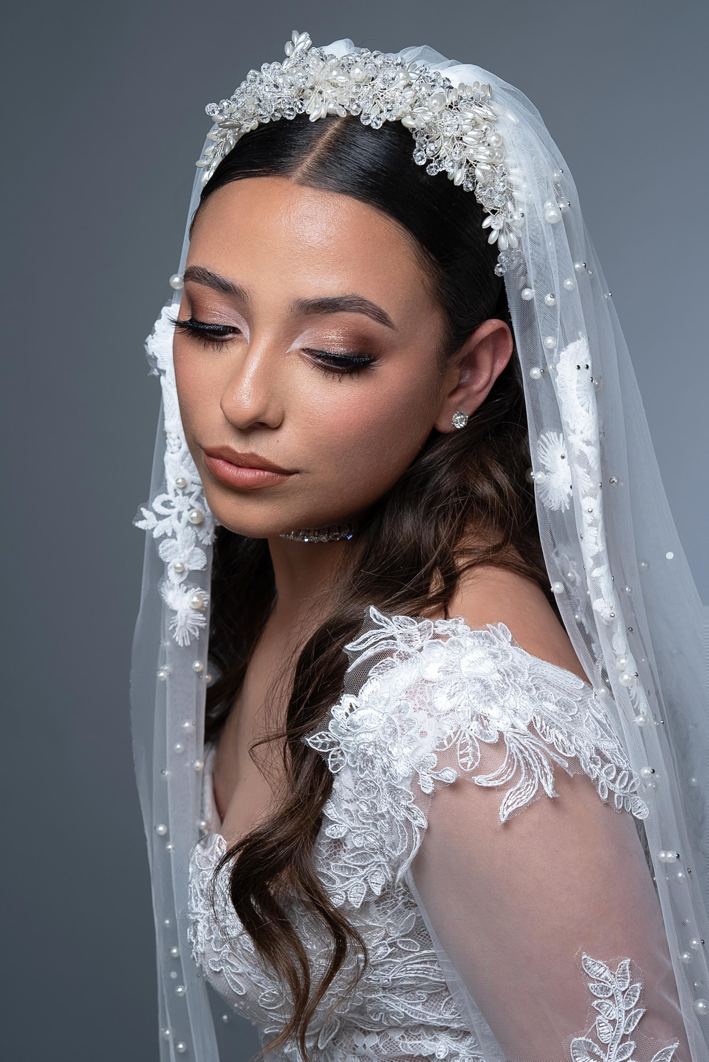Novia de perfil con velo de perlas y encaje, mirada baja