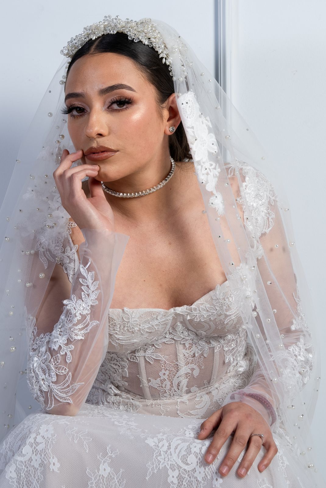 Novia sentada con velo de perlas y vestido de encaje