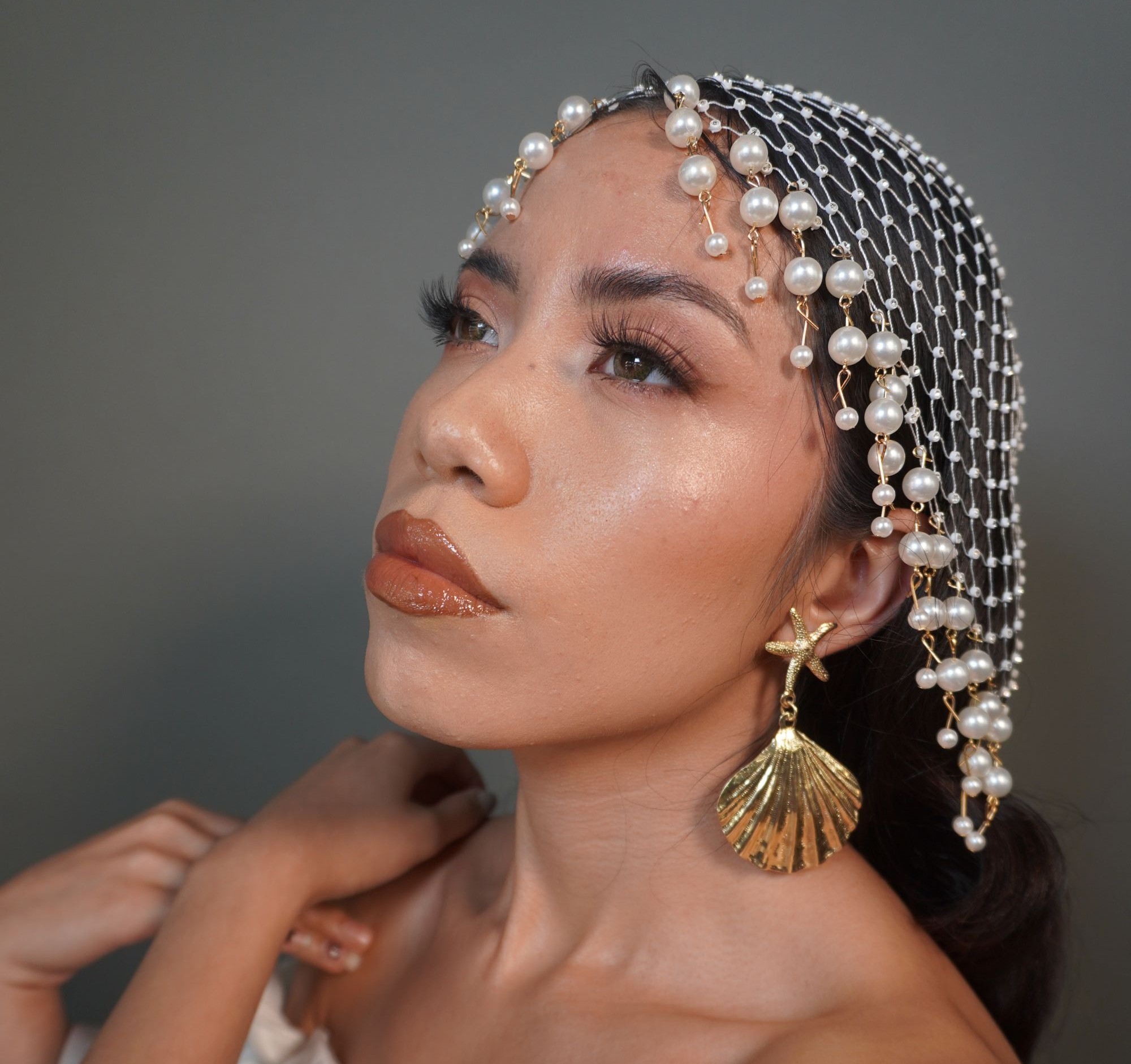 Novia con tocado de perlas tipo casquete y aretes dorados de concha