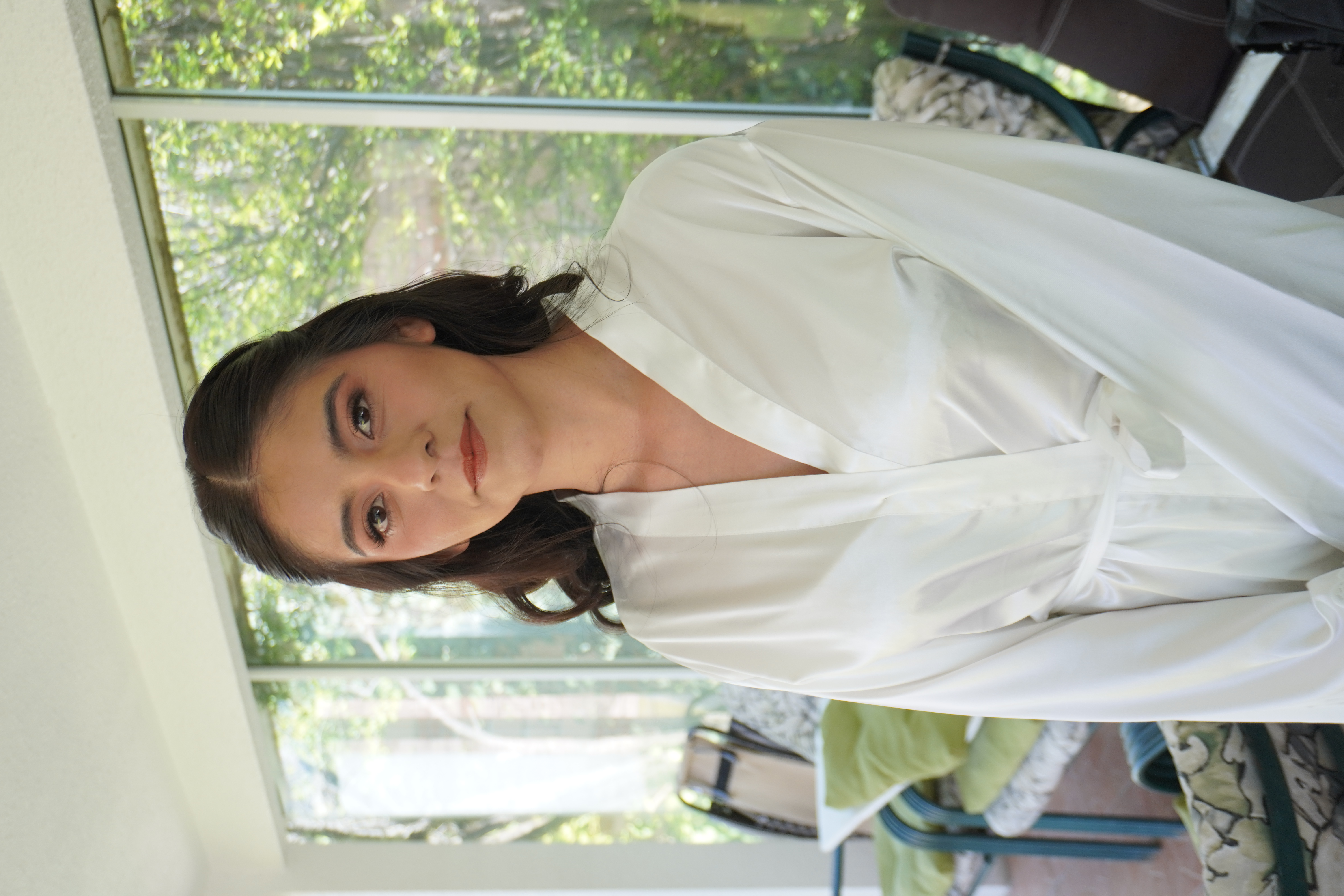 Novia en bata junto a la ventana con luz natural