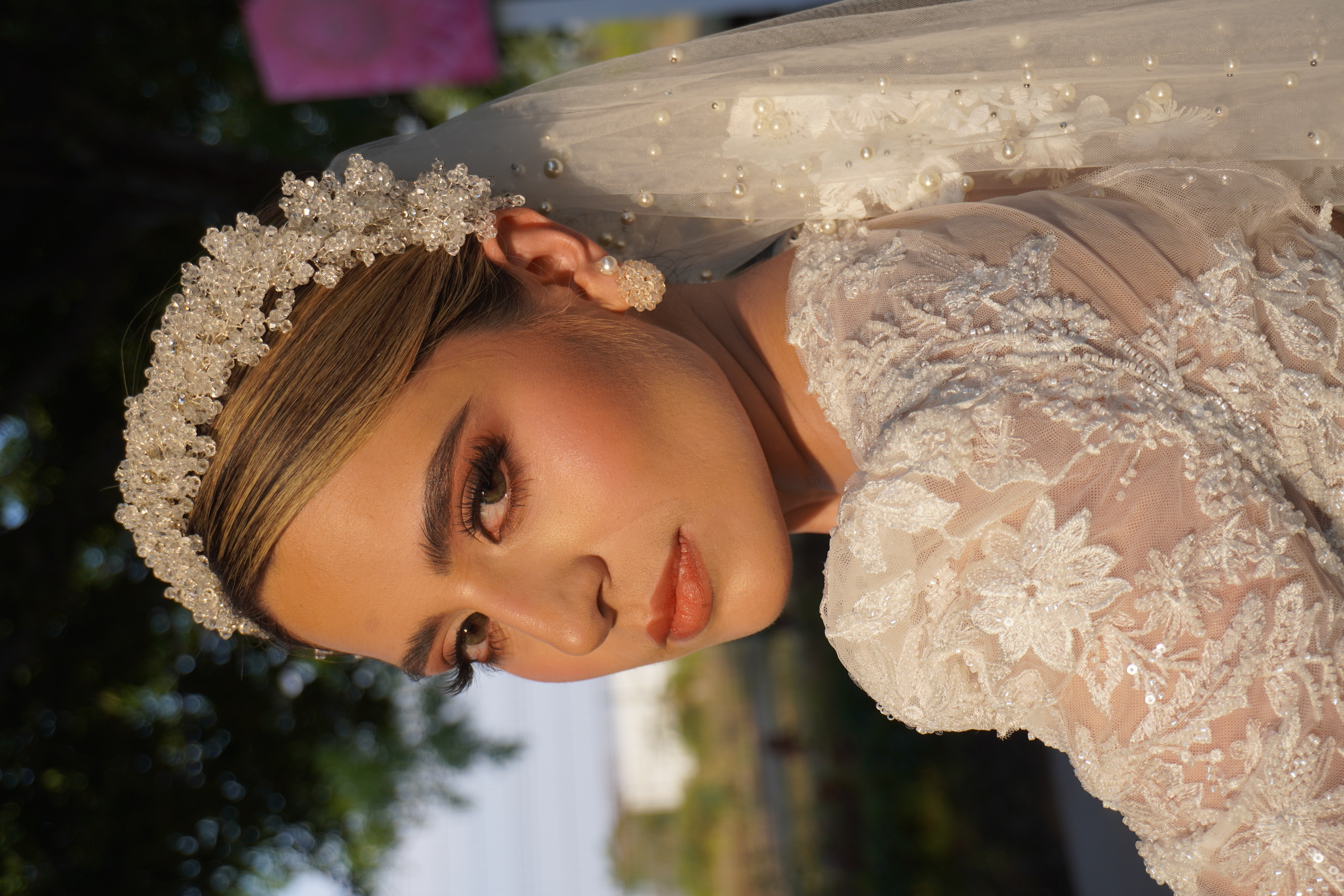 Novia con corona de cristales y velo bajo luz calida de atardecer