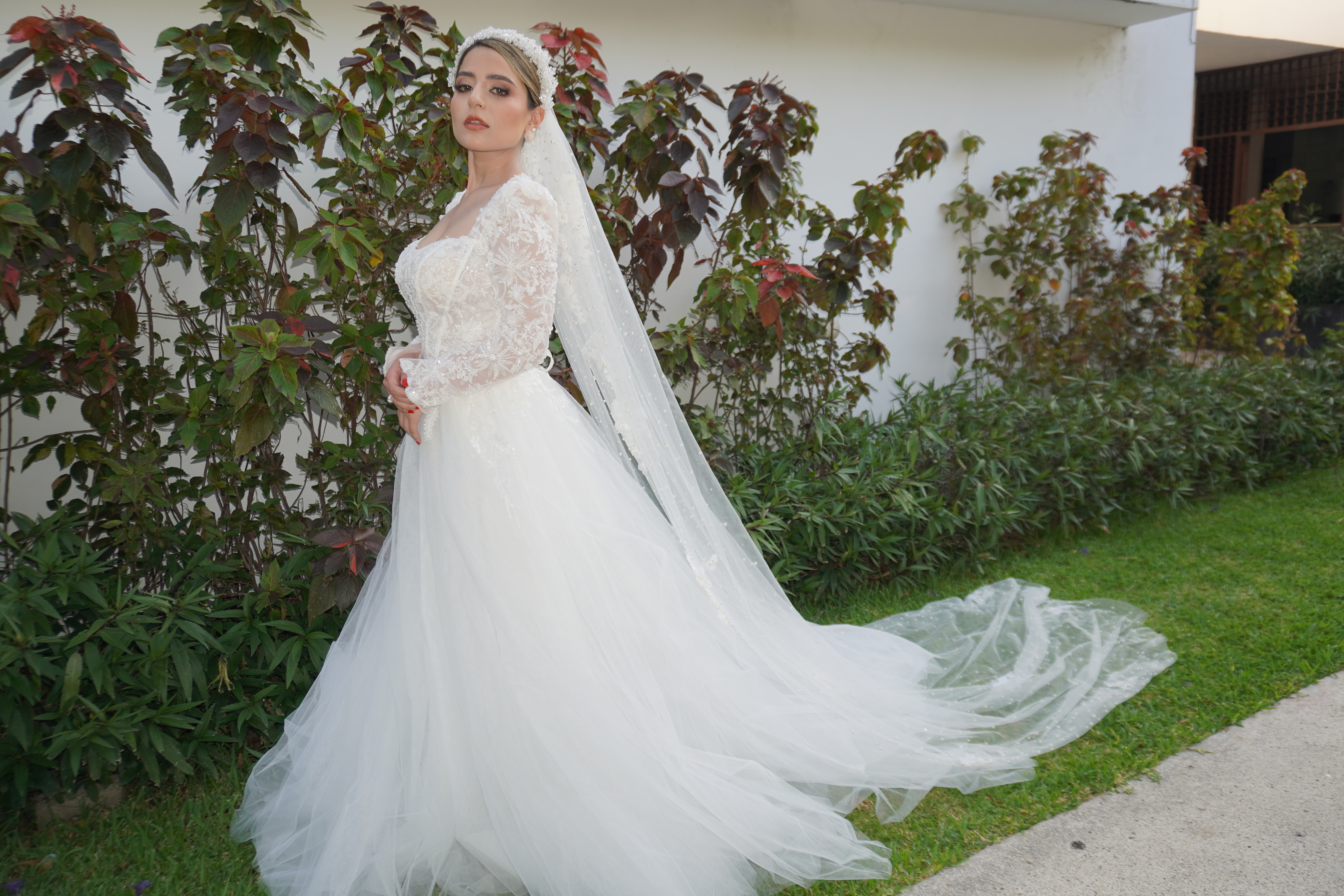Novia con vestido completo y cola larga en un jardin