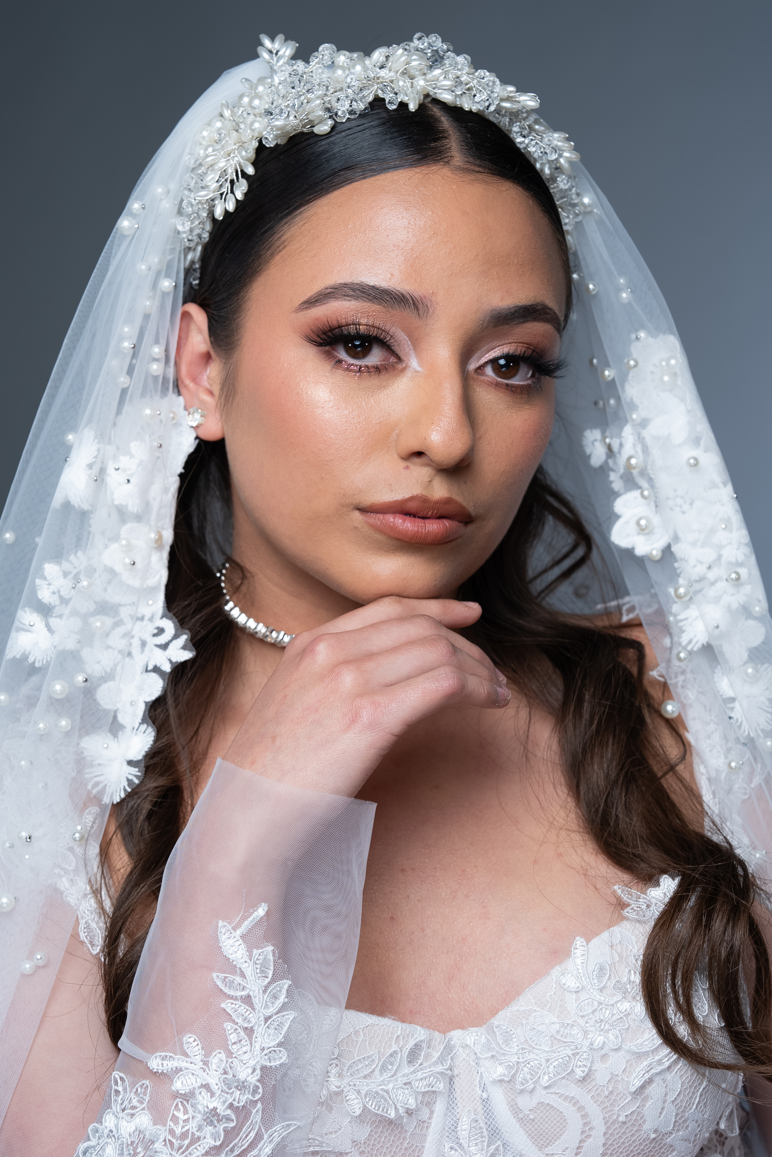 Novia con velo de perlas y maquillaje luminoso en retrato editorial