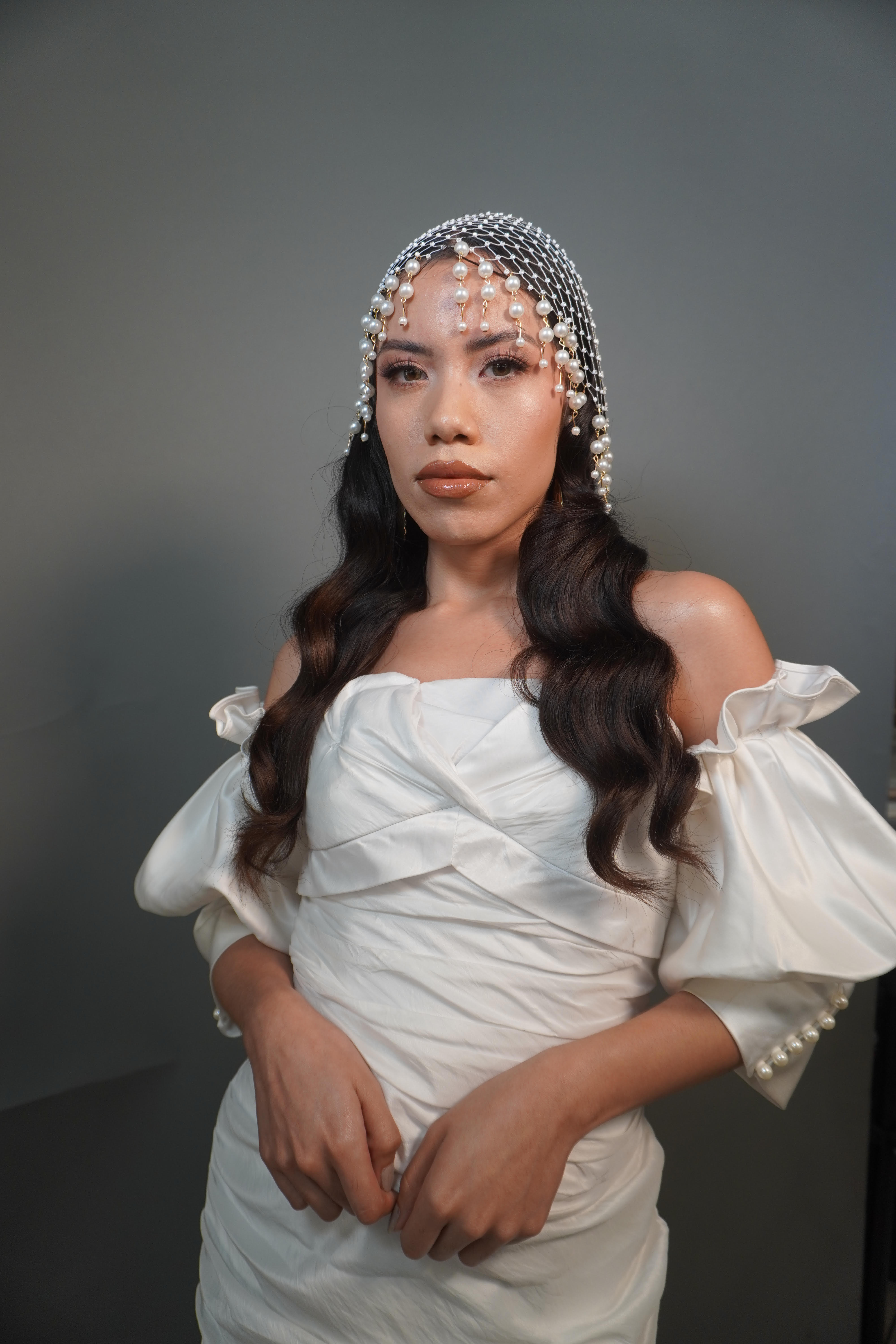 Novia con tocado de perlas y ondas suaves sobre vestido de saten