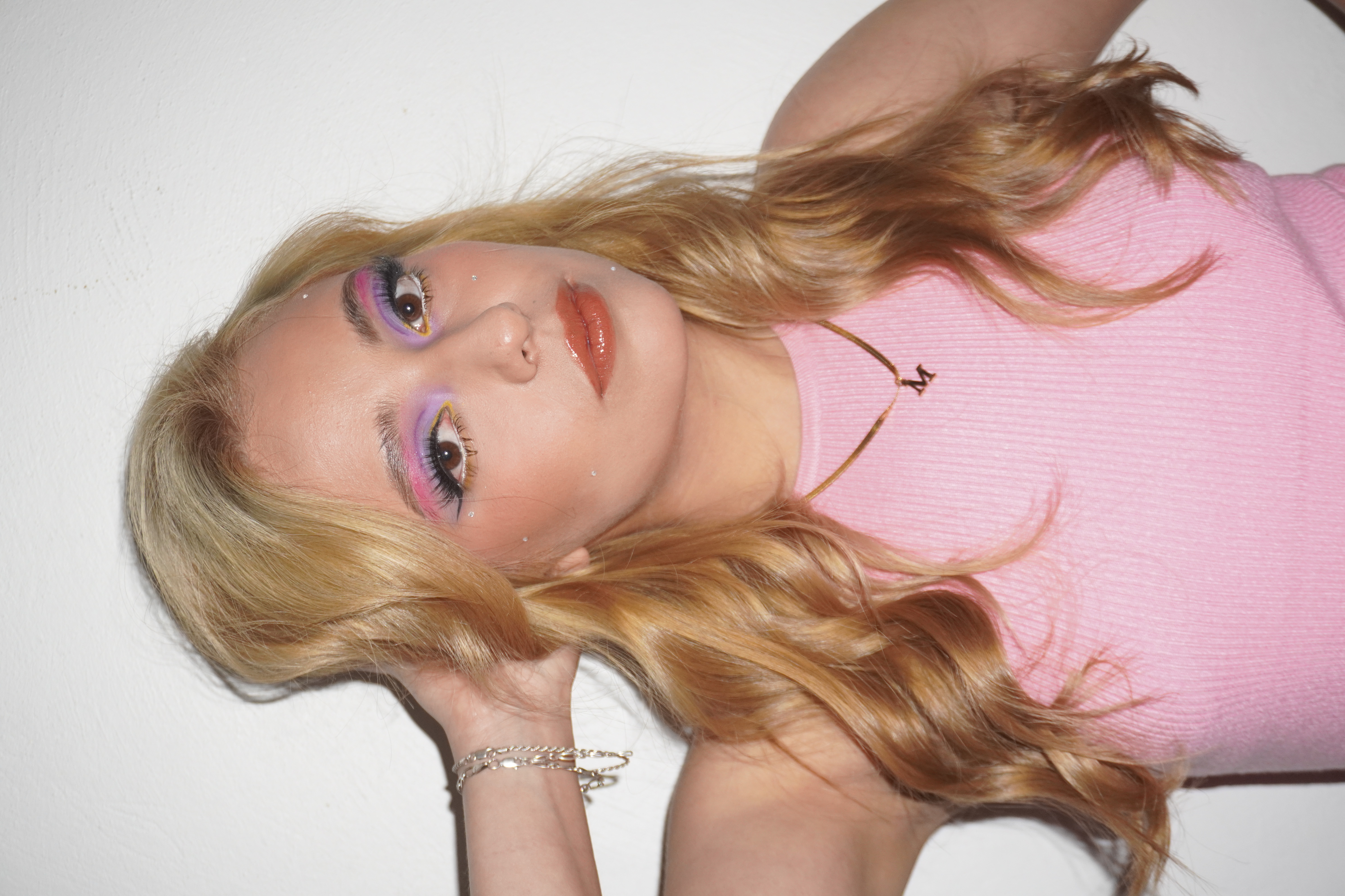 Maquillaje editorial con delineado rosa y amarillo y cristales